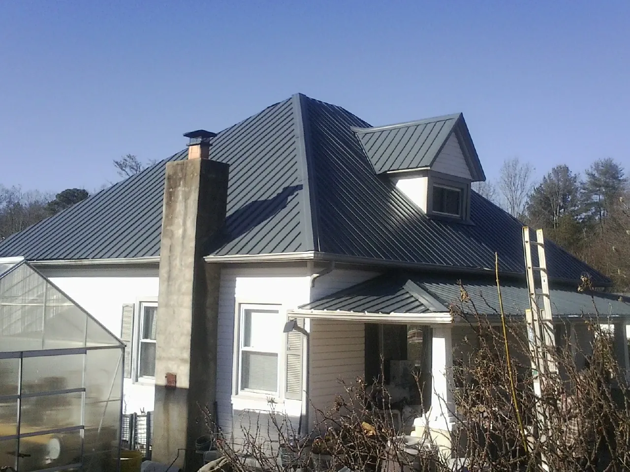 Dark blue standing seam metal roof on a white farmhouse with dormer — Slate & Tile Roof Repair by Roofing Brothers in Cynthiana