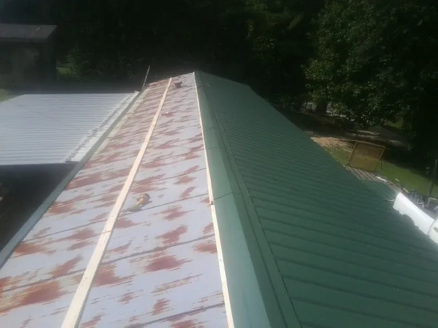 Old rusted panels beside newly installed green metal roofing — Wind Damage Roof Repair by Roofing Brothers in Cynthiana