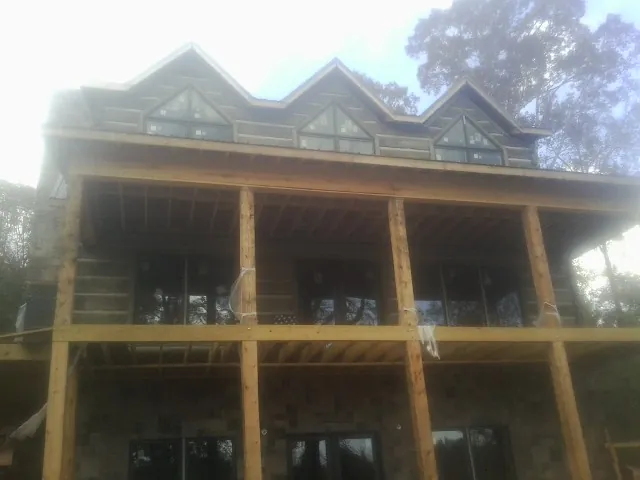 Dormers and porch framing on a large log home under construction — Roof Coating work by our crew in Cynthiana