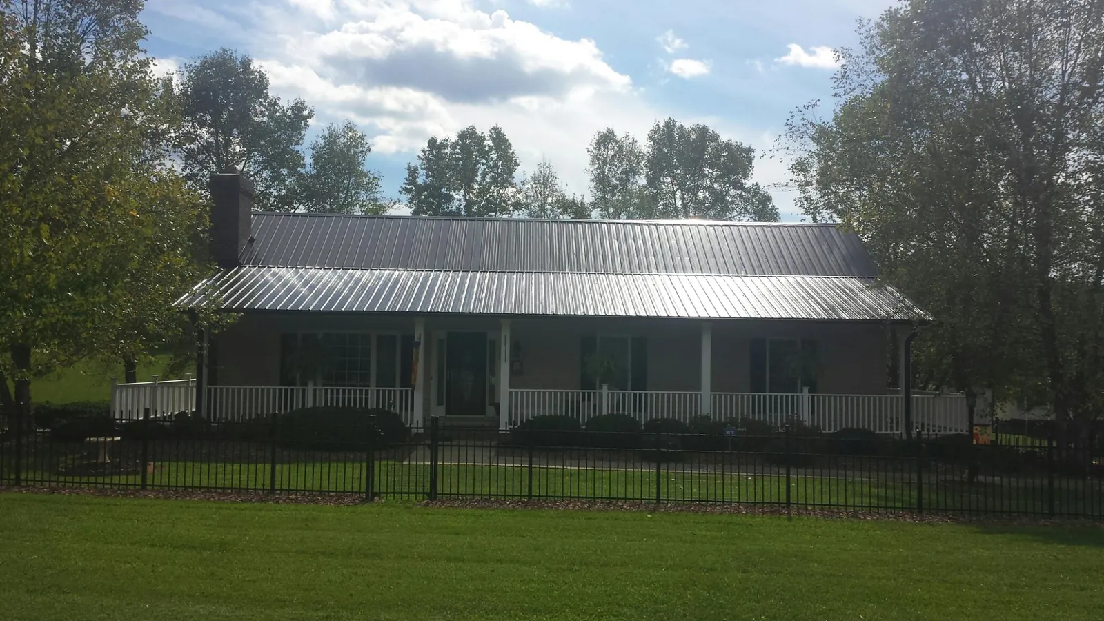 Gray metal roof on a brick ranch with a full width front porch in Cynthiana