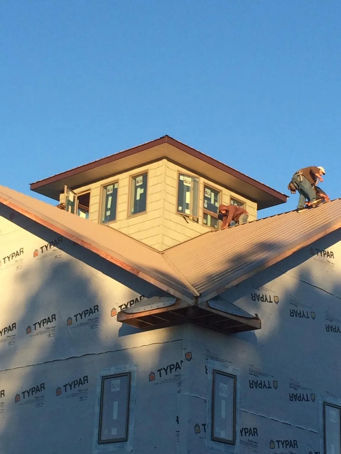 Roofers working around a rooftop cupola on a new metal roof at sunset — Roof Waterproofing in Cynthiana by Roofing Brothers